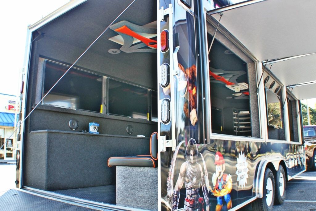 Mobile trailer with open windows and superhero-themed graphics. Interior view shows counter and seating.