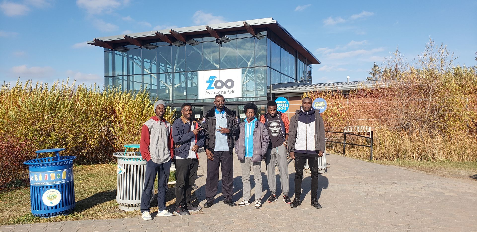 A group of young men are standing in front of the winnipeg zoo building.