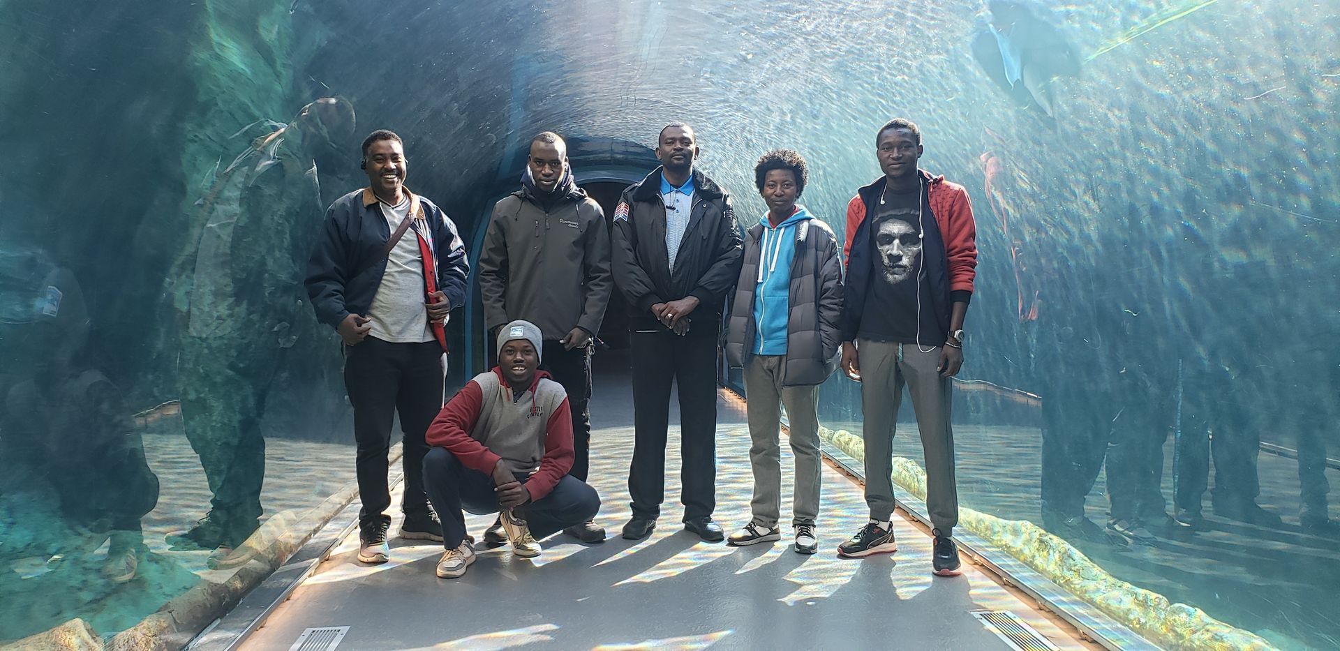 A group of men are posing for a picture in front of an aquarium.