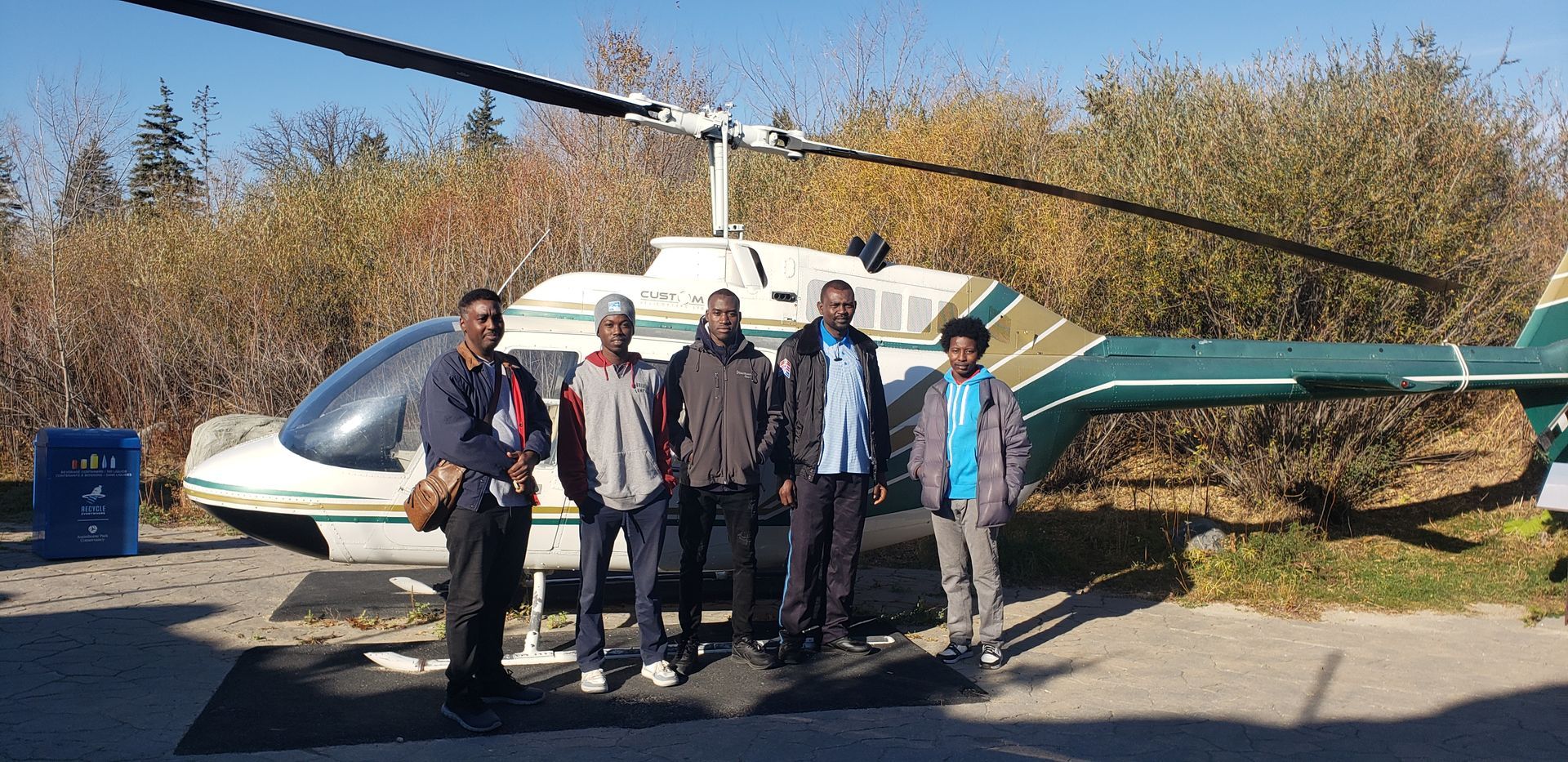 A group of men are standing in front of a helicopter.