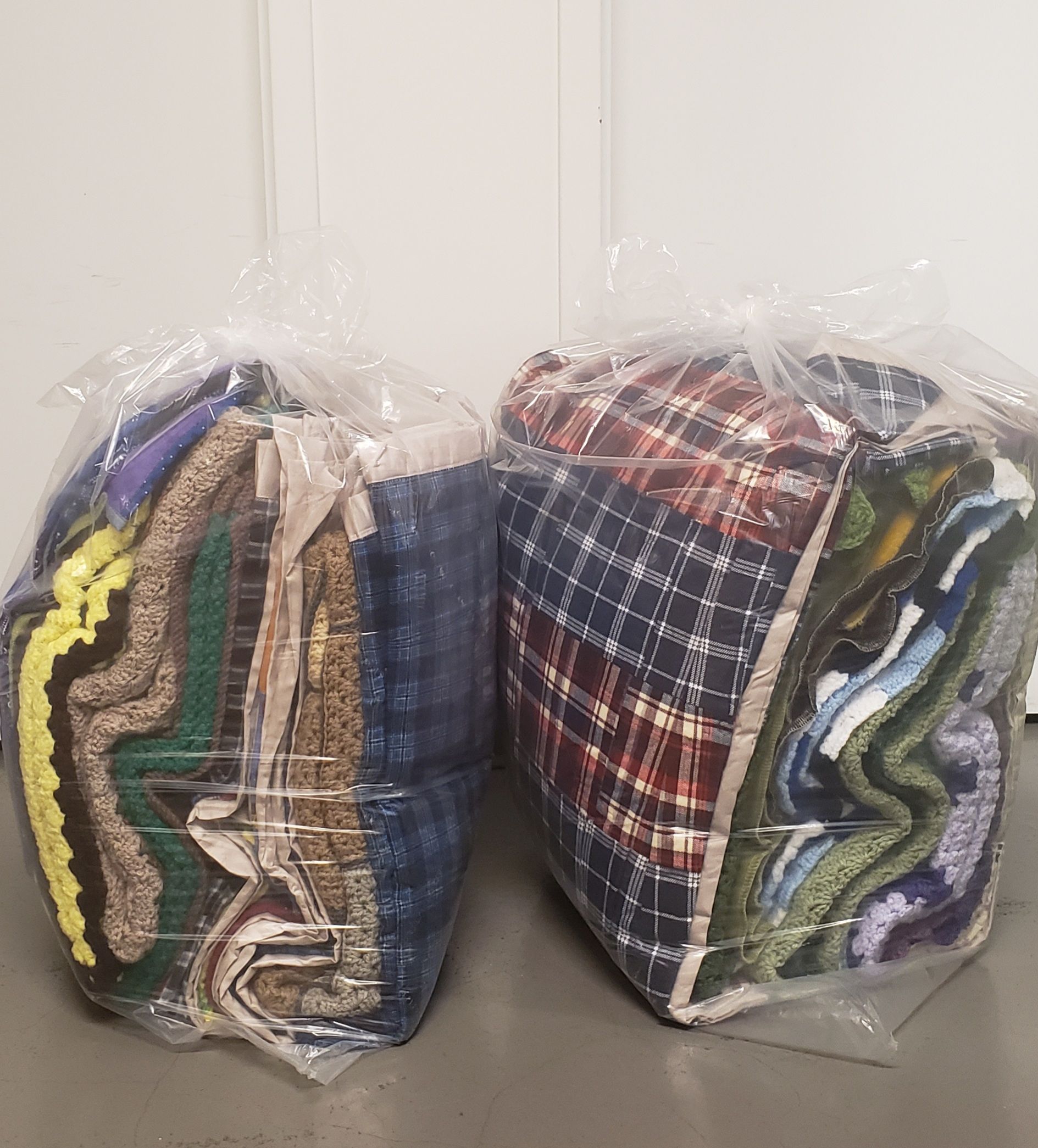 Two bags of clothes are stacked on top of each other on a table.