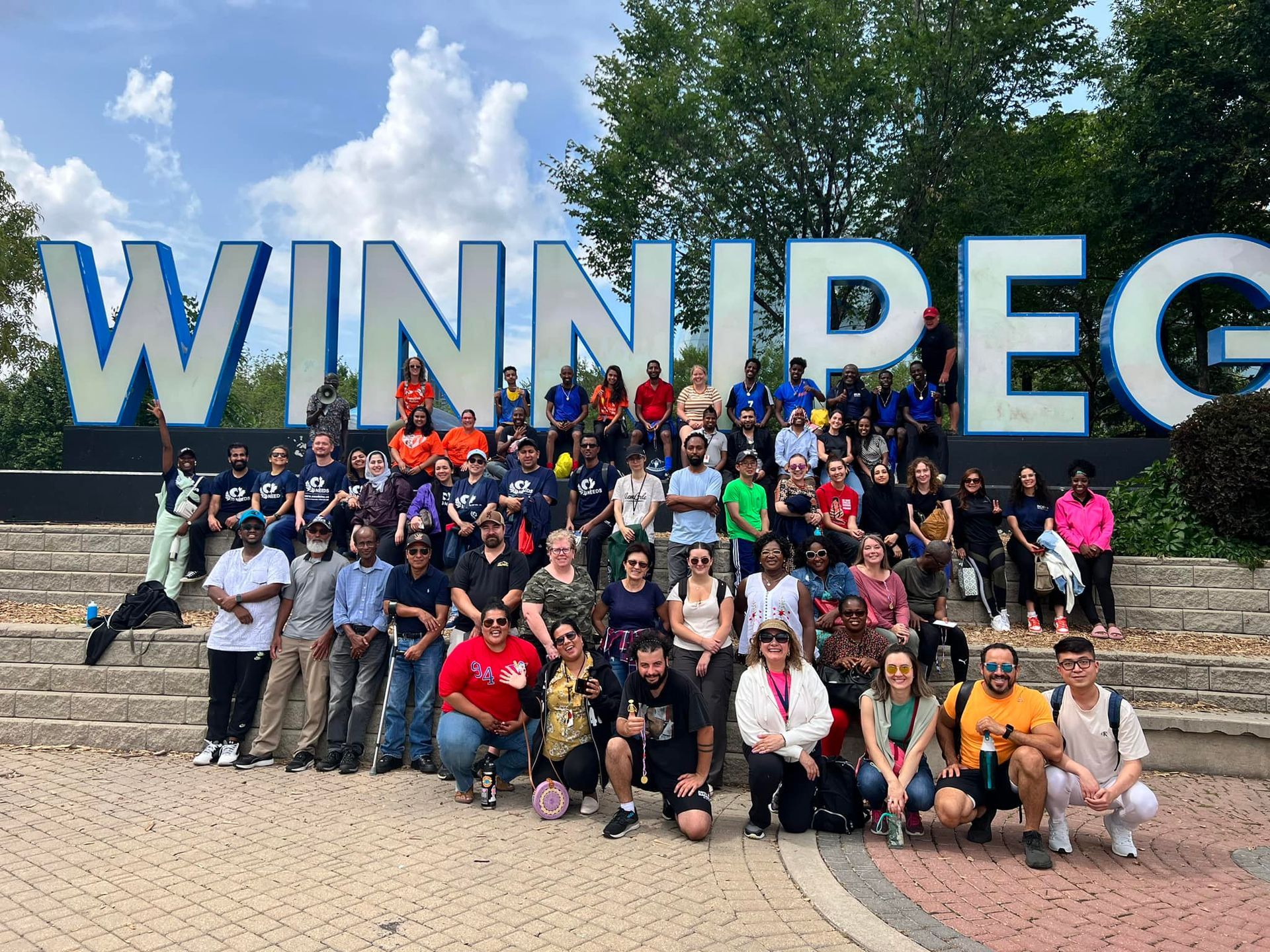 A group of people are posing for a picture in front of a sign that says winnipeg.