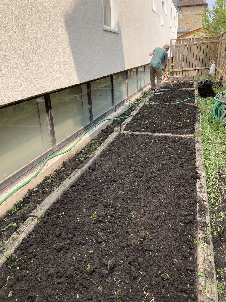 A man is working in a garden next to a building.