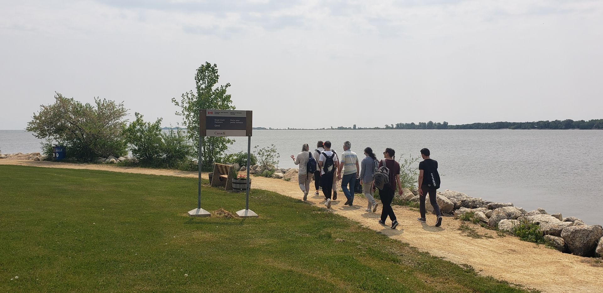 A group of people are walking along a path next to a body of water.
