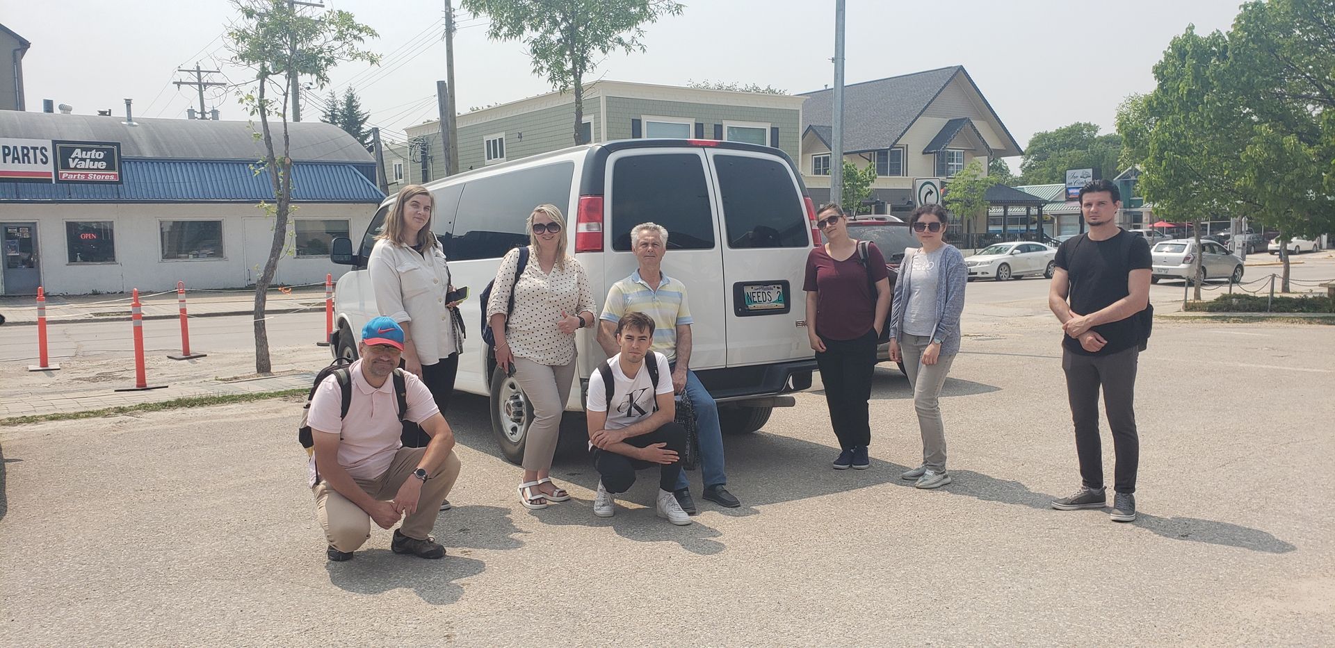 A group of people are posing for a picture in front of a van.
