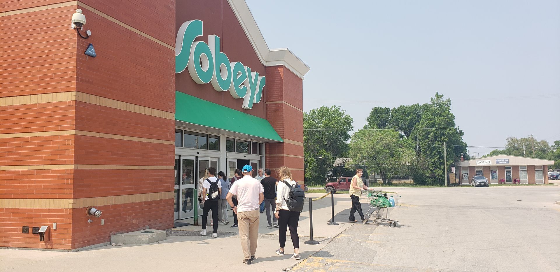 A group of people are standing outside of a grocery store.