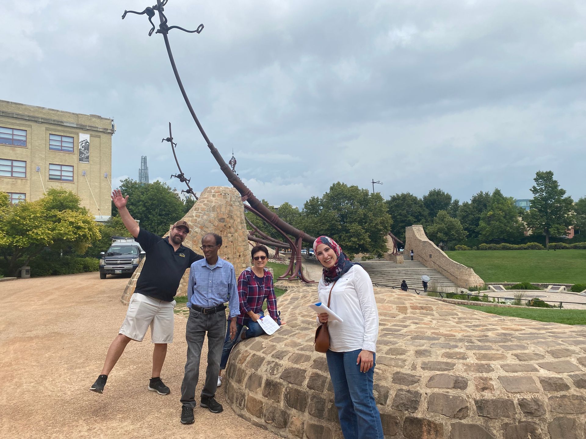 A group of people are posing for a picture in front of a sundial.