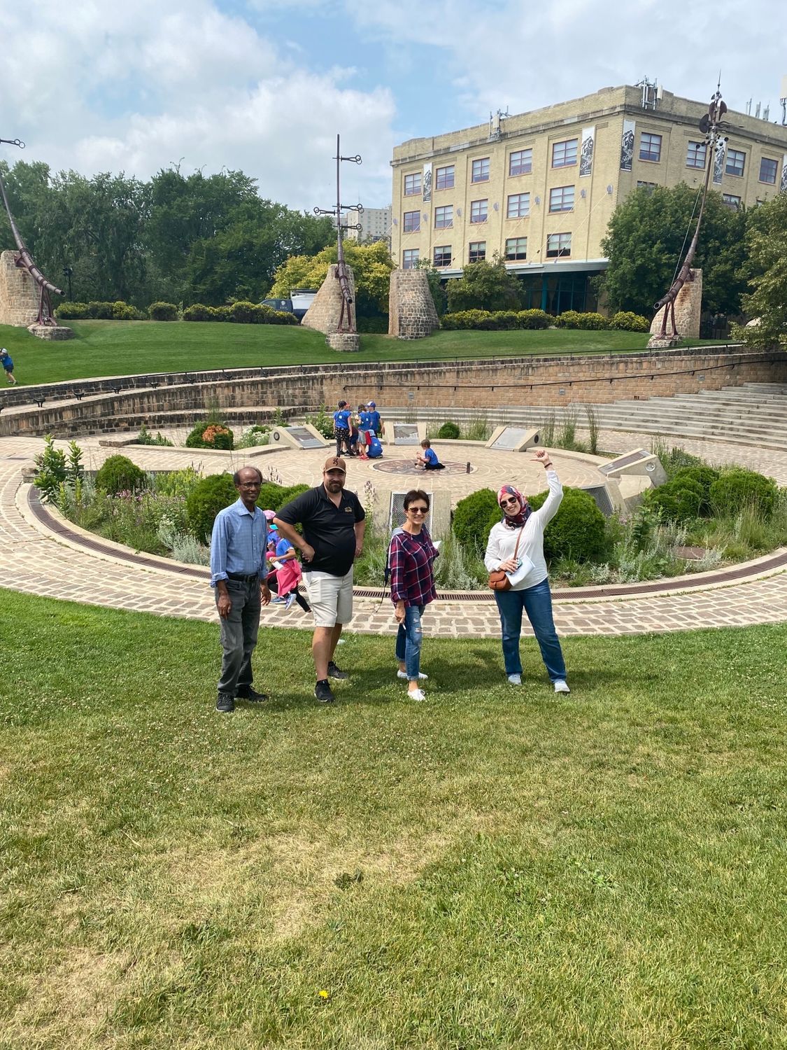 A group of people are standing in a park in front of a building.