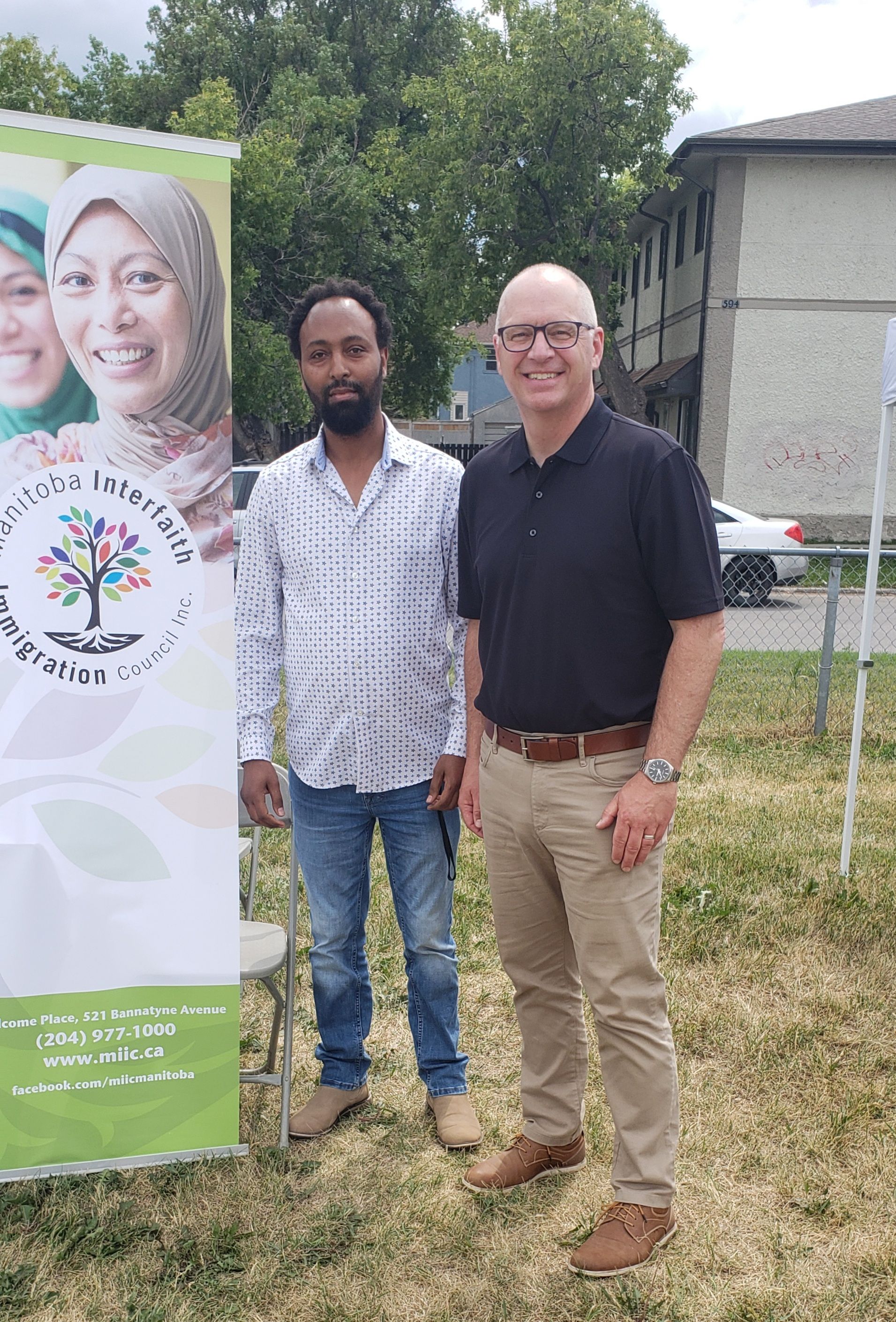 Two men are standing next to each other in front of a banner.