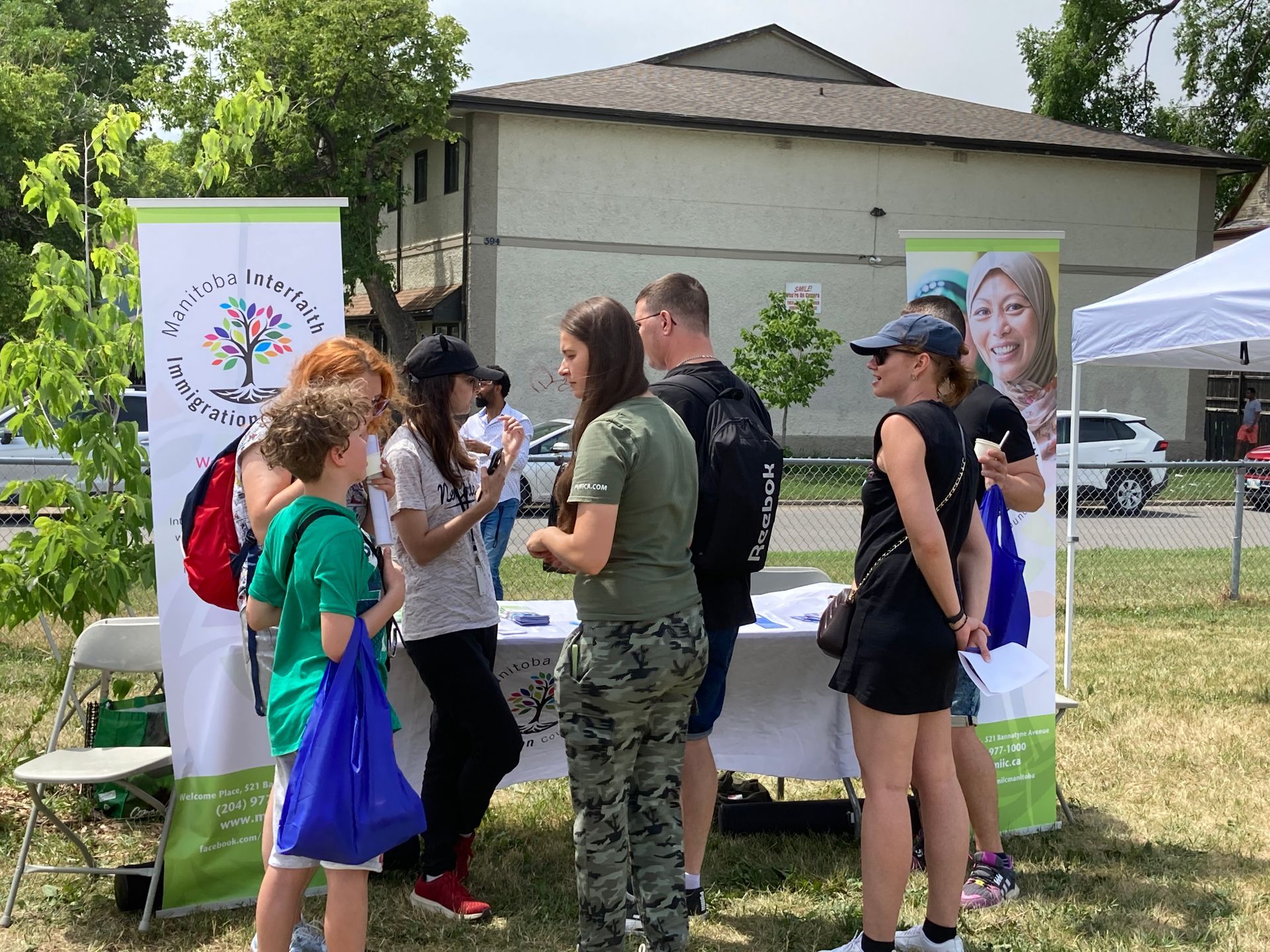 A group of people are standing around a table in a park.