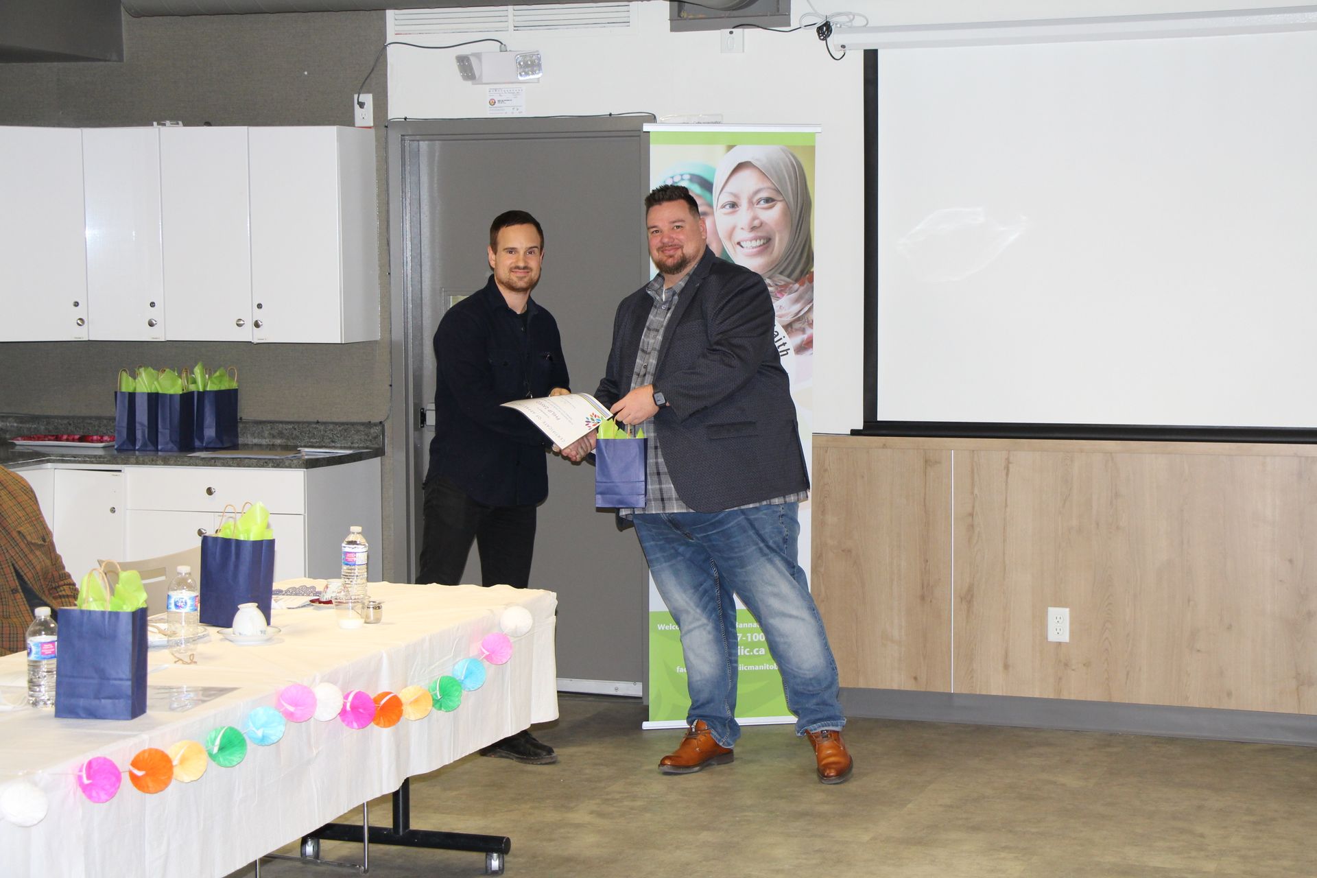 Two men are standing next to each other in a room holding a certificate.