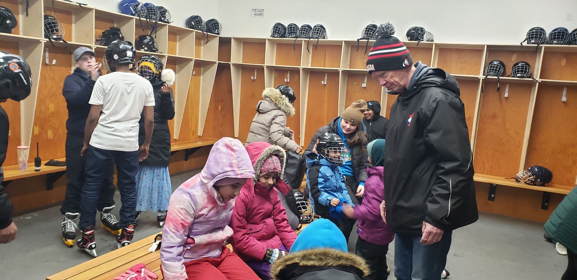 A group of people are standing and sitting in a locker room.