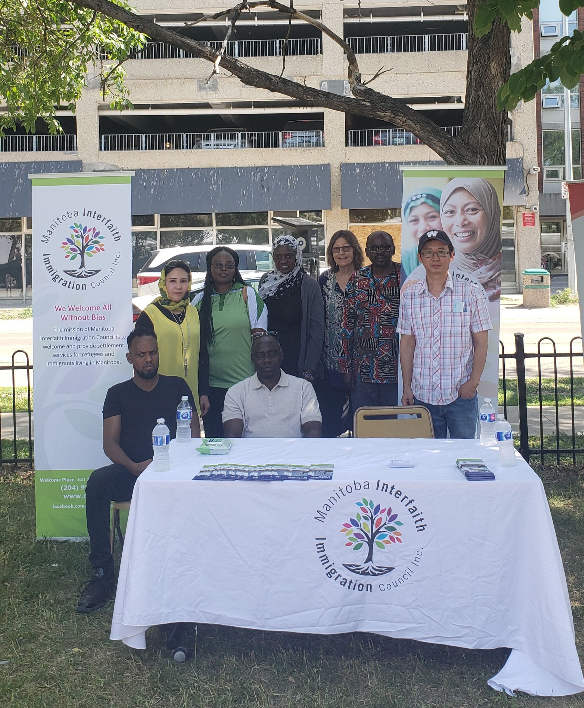 A group of people are standing around a table in a park.