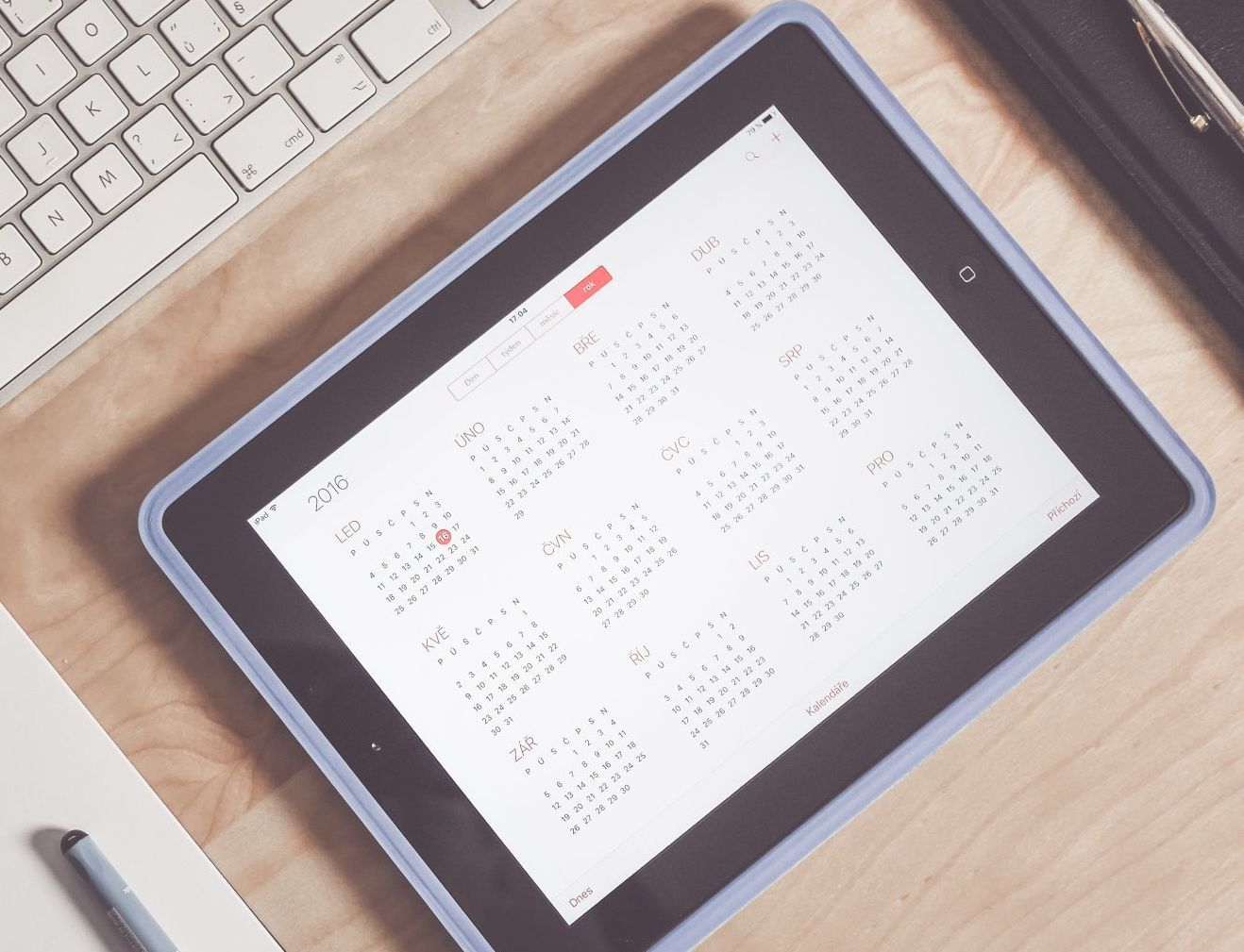 A tablet with a calendar on it sits on a desk next to a keyboard