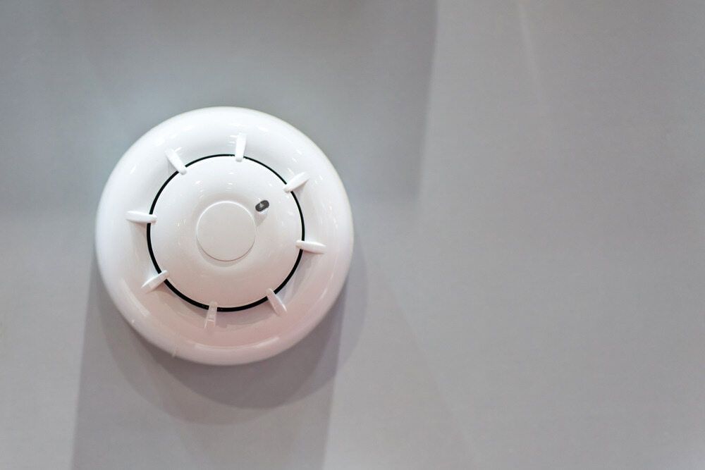 A White Smoke Detector is Hanging on a Gray Wall — East-West Fire Services In Charters Towers, QLD