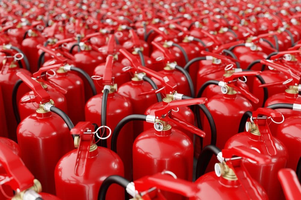 A Bunch of Red Fire Extinguishers Are Lined Up in a Row — East-West Fire Services In Mount Isa, QLD