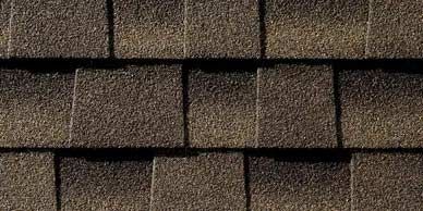 Close-up of dark brown asphalt roof shingles, with a rough textured surface, arranged in rows.