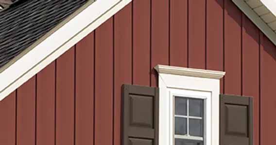 Red vertical siding on a house with white trim, brown shutters, and a window.