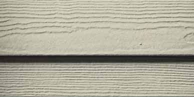 Close-up of horizontal, light beige siding boards with dark shadow line.