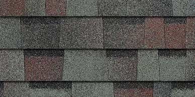 Close-up of overlapping asphalt roof shingles in shades of gray, red, and green.