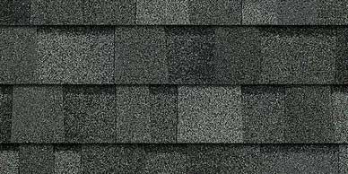 Close-up of dark gray asphalt roof shingles, showing textured surface and layered pattern.