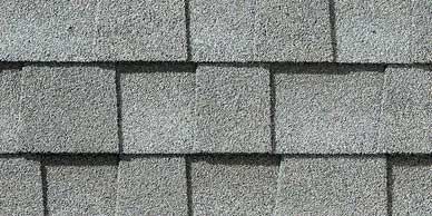 Close-up of gray asphalt roof shingles with a rough, textured surface.