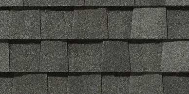Close-up of gray asphalt roofing shingles, showing overlapping layers and granular texture.