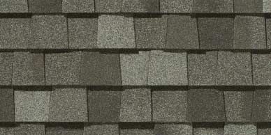 Close-up of asphalt roof shingles with a speckled pattern in various shades of gray.