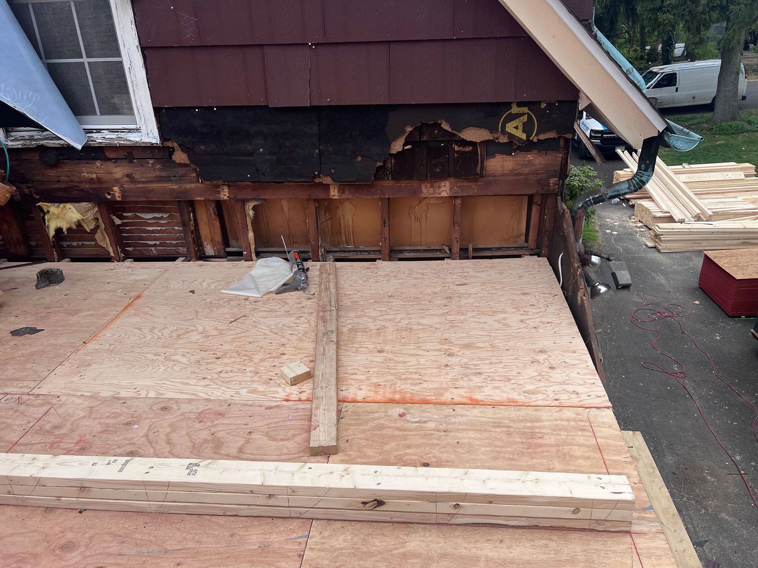 Construction site with exposed wall, plywood, and building materials. Brown and natural tones.