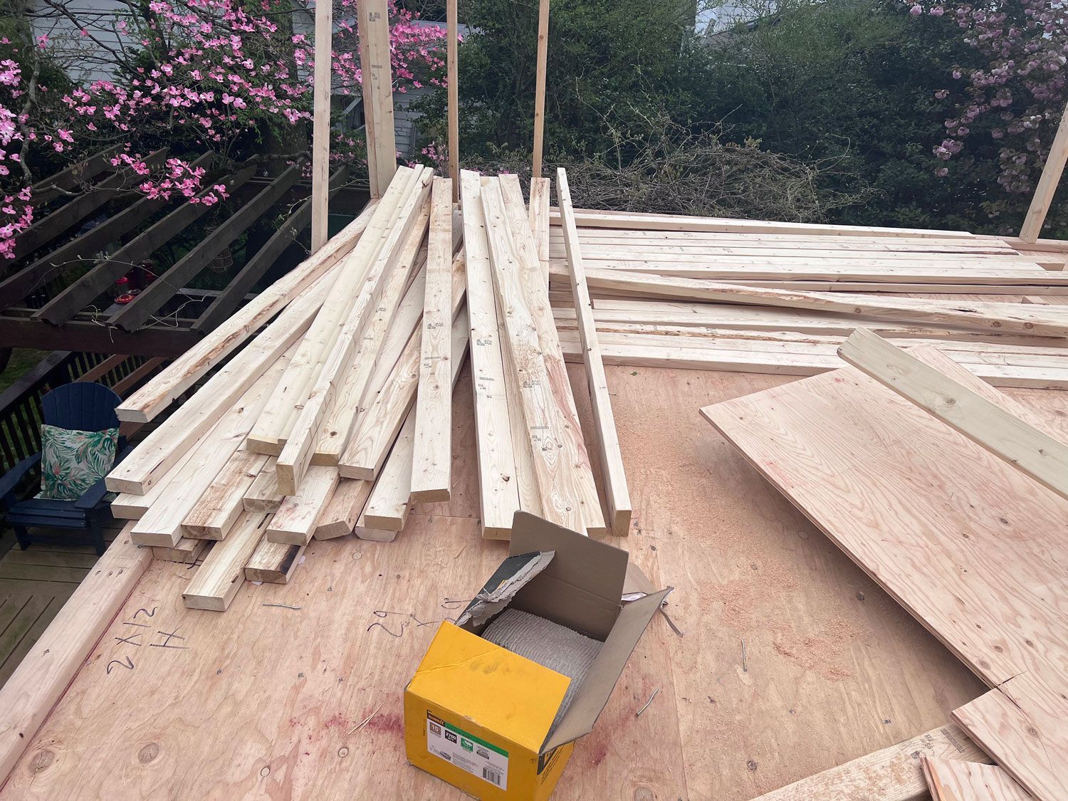 Wooden planks and plywood stacked on a roof; construction materials for a building.