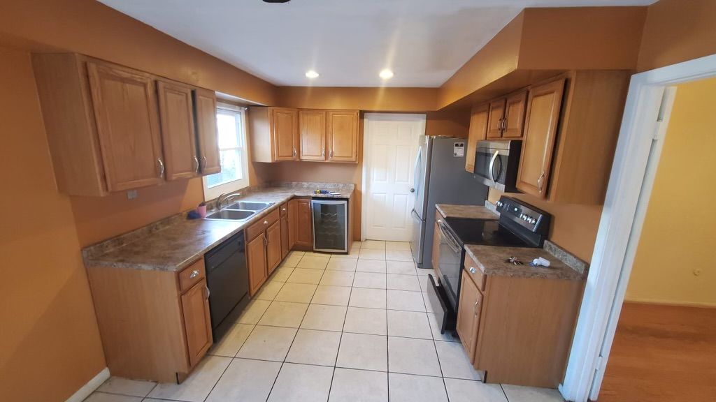 Kitchen with wood cabinets, stainless steel appliances, and tile floor.