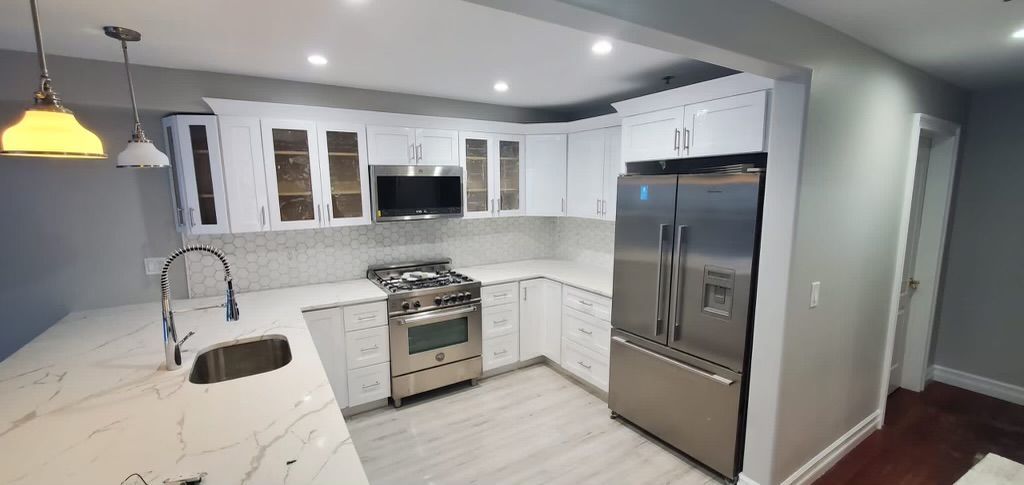 White kitchen with stainless steel appliances, quartz countertops, and two pendant lights.