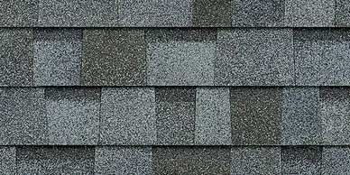 Close-up of a roofing tile pattern in varying shades of gray, with a slightly rough texture.