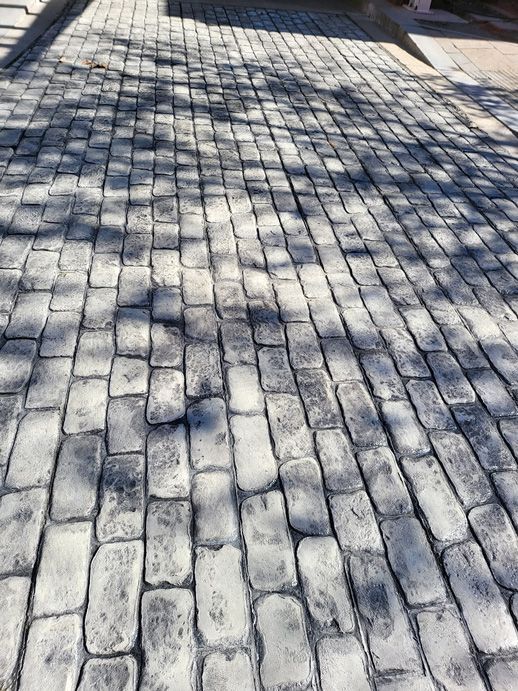 Cobblestone pavement with shadows from overhead trees.