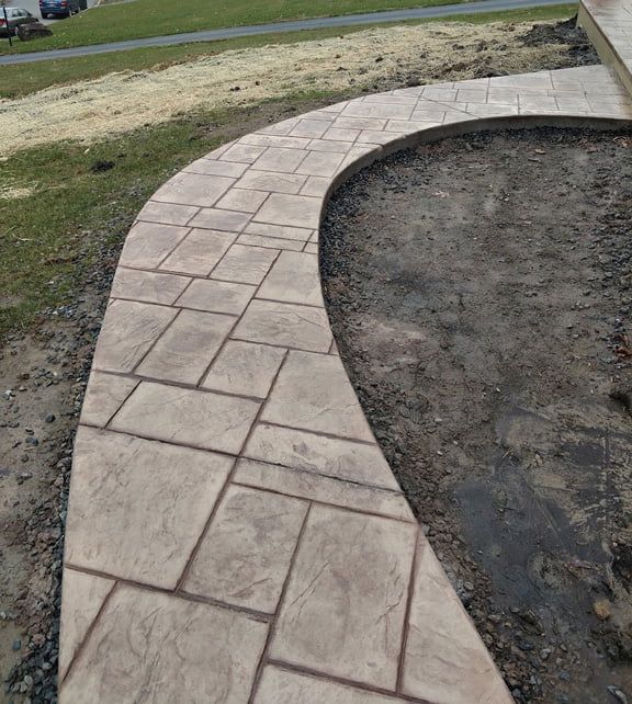 Stamped concrete walkway in a random stone pattern, light brown color.