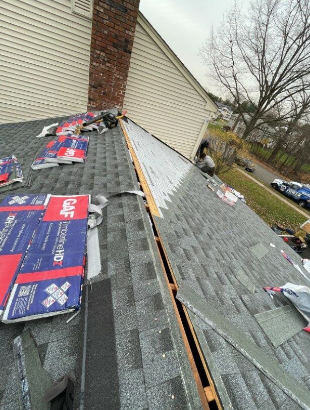 Roofing project with removed shingles, GAF shingle boxes, and partial new shingle installation.
