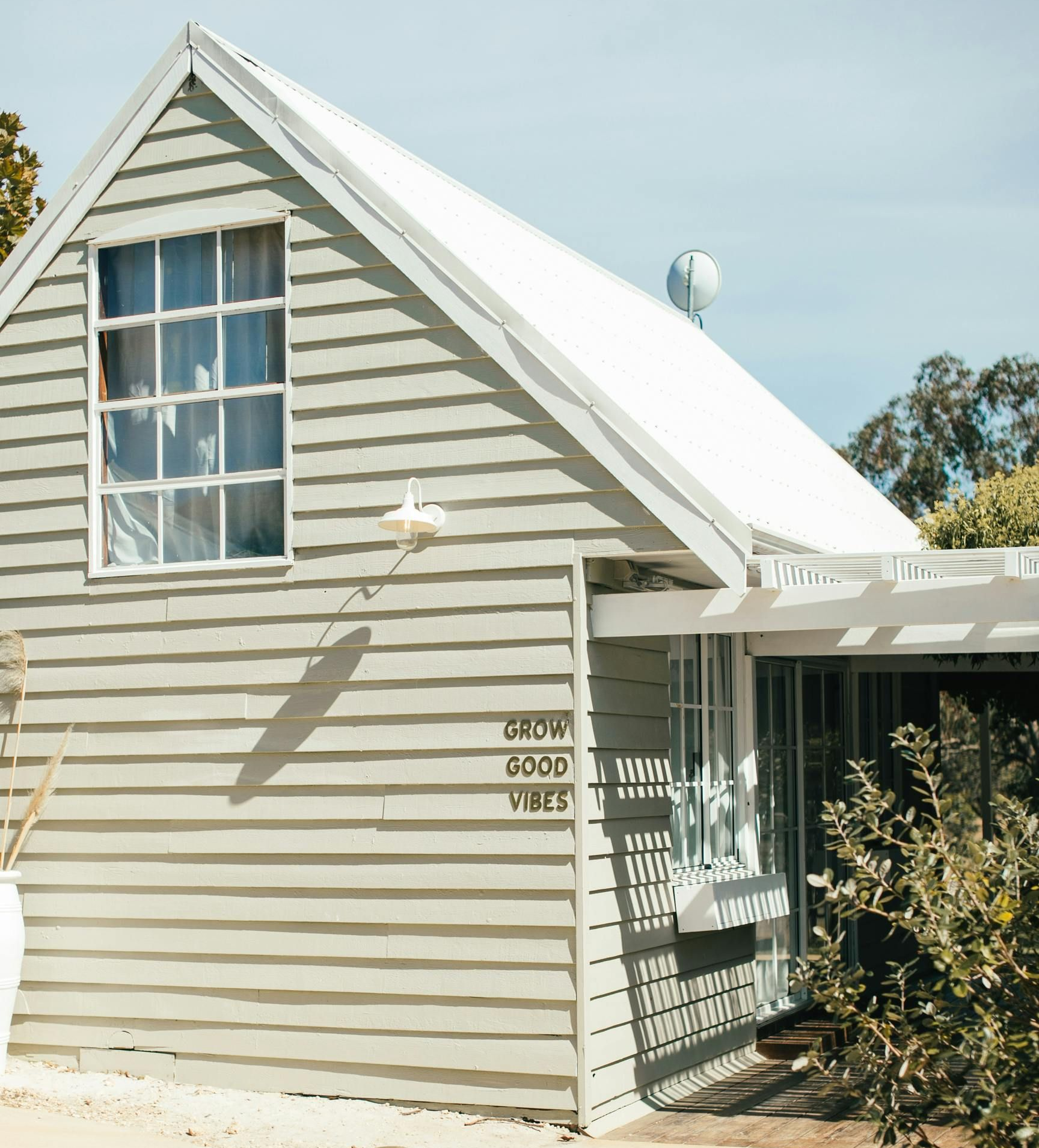 Gray wooden house with white roof and a window.