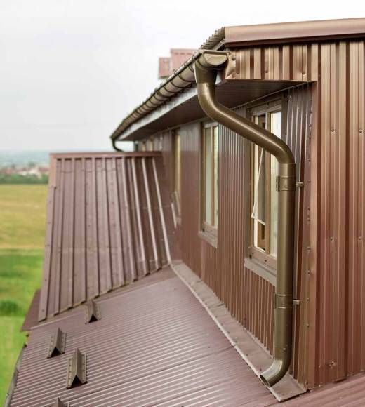 Brown metal roof with matching gutters and downspout on a building.
