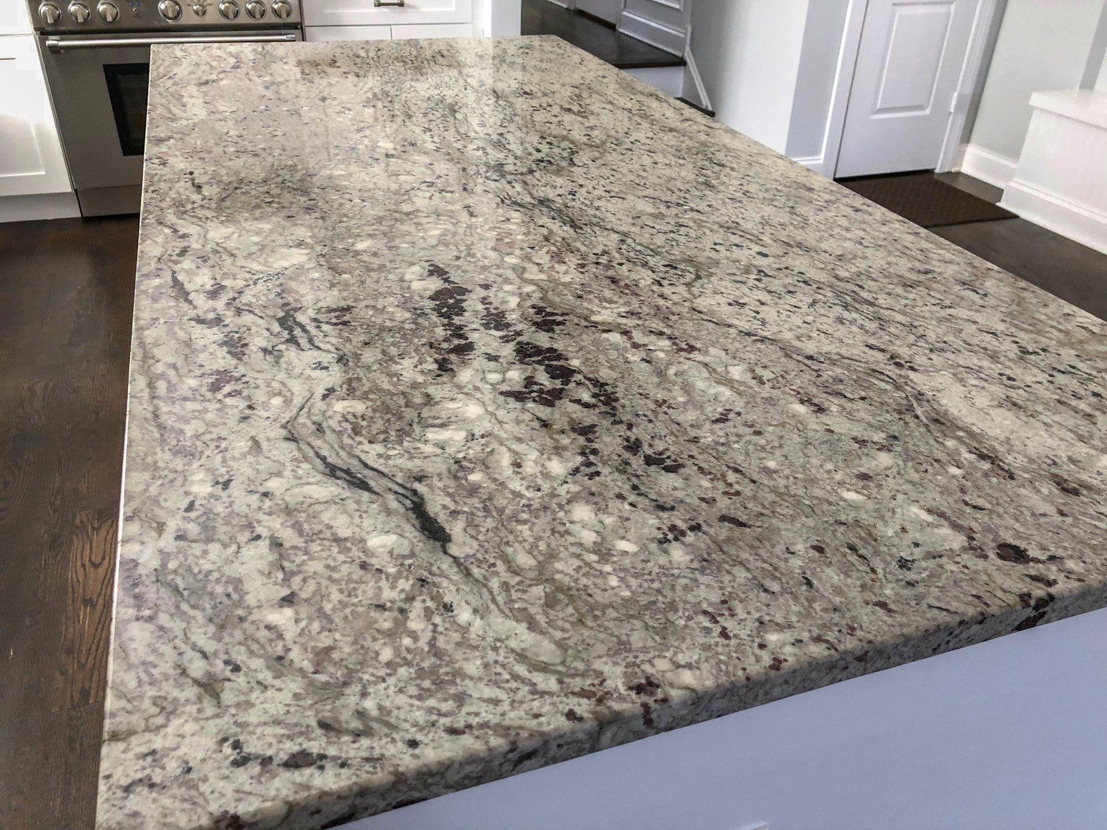 Granite countertop with swirling gray, white, and brown patterns in a kitchen.