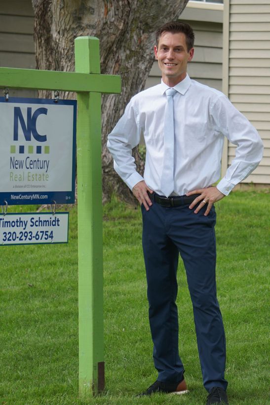 Tim Schmidt, a REALTOR® standing next to a yard sign.