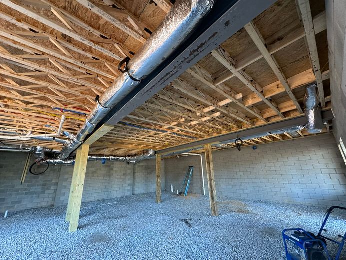 A basement under construction with a lot of pipes coming out of the ceiling.