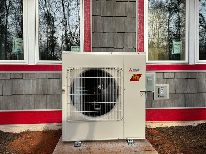 A white air conditioner is sitting on the side of a building.