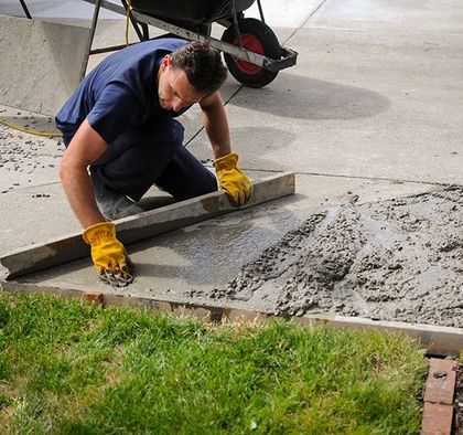 a man wearing yellow gloves is working on a sidewalk