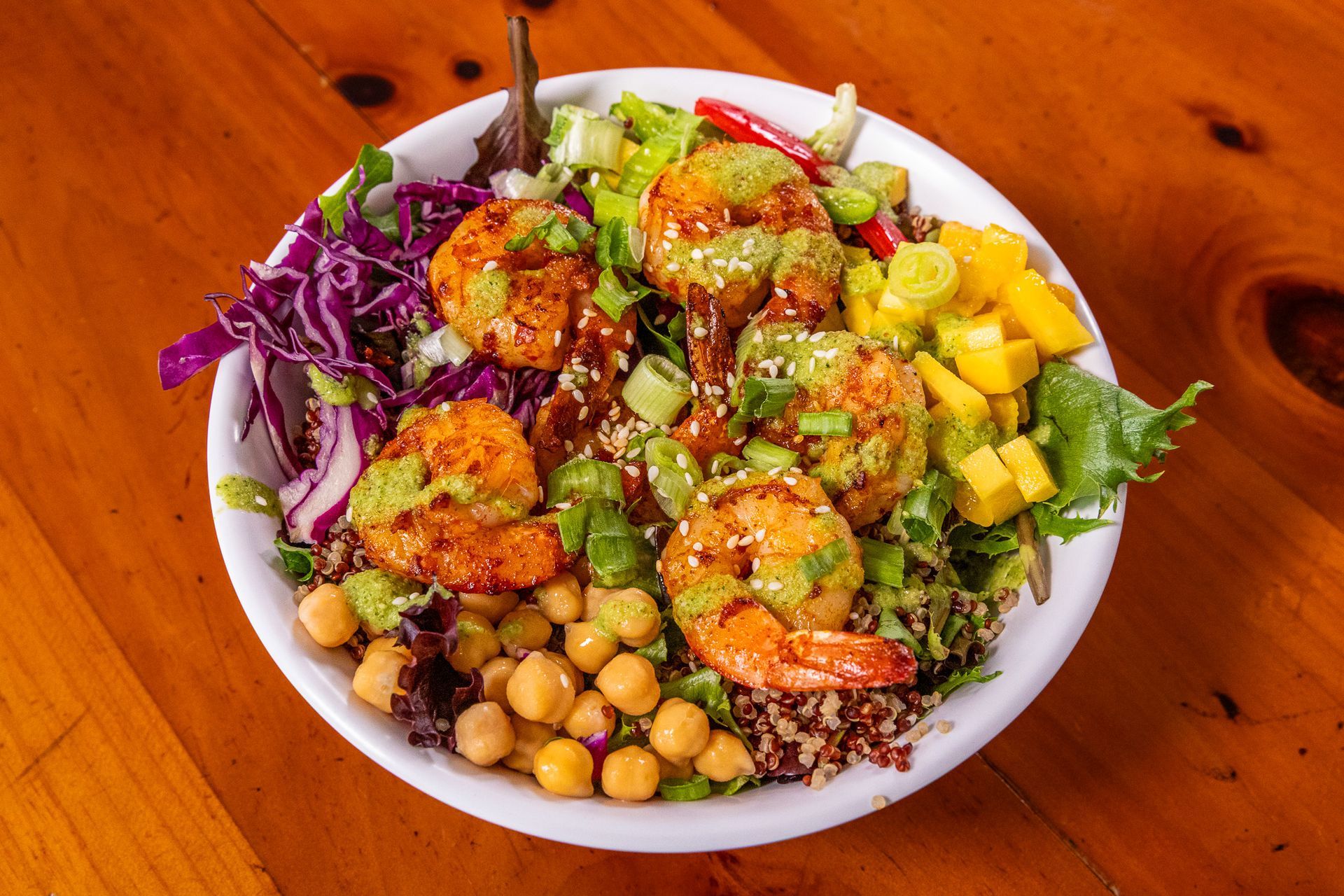 Bowl with grilled shrimp, chickpeas, mango, red cabbage, and quinoa.