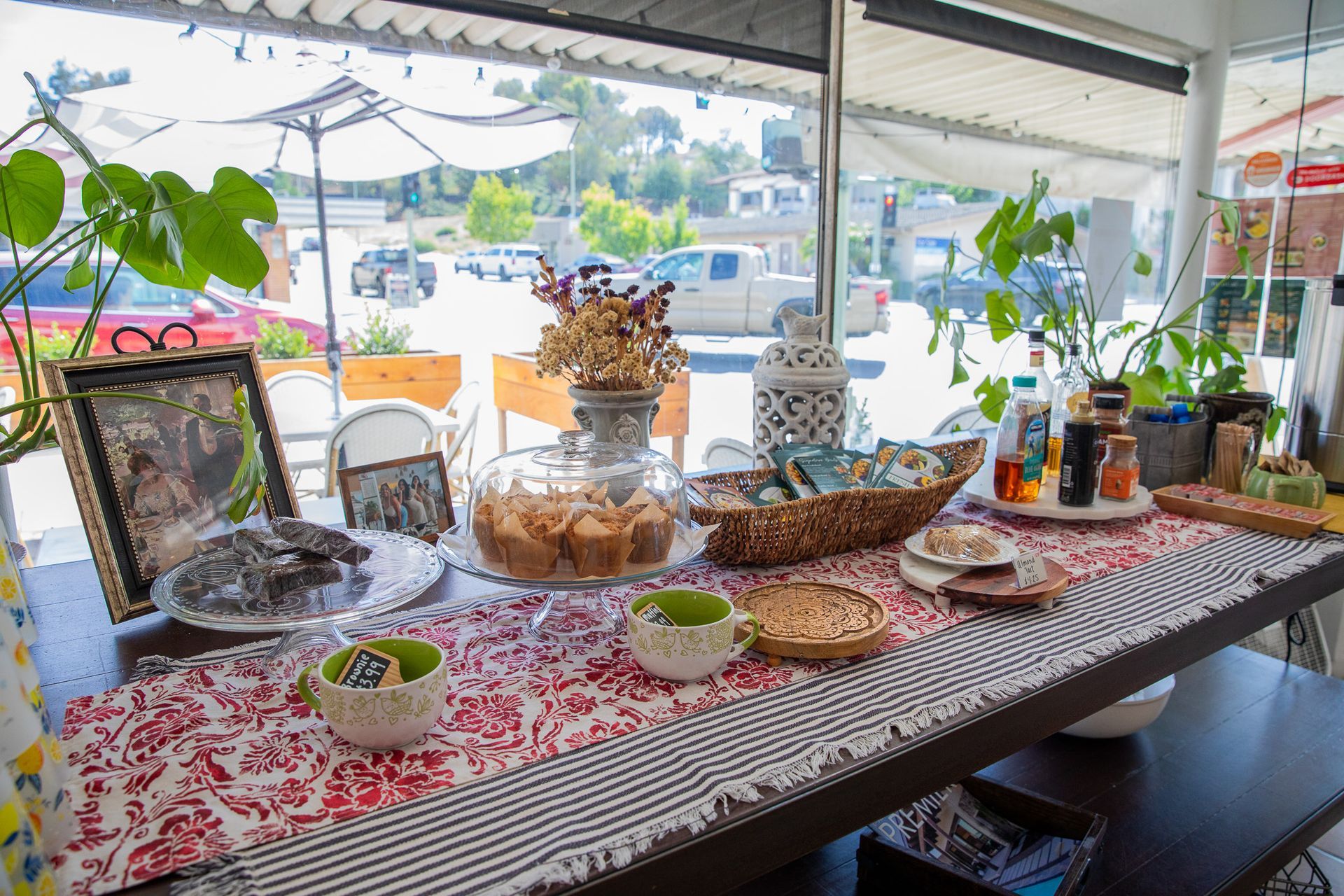 Table with cookies, teacups, and decorations in front of a window overlooking a street.