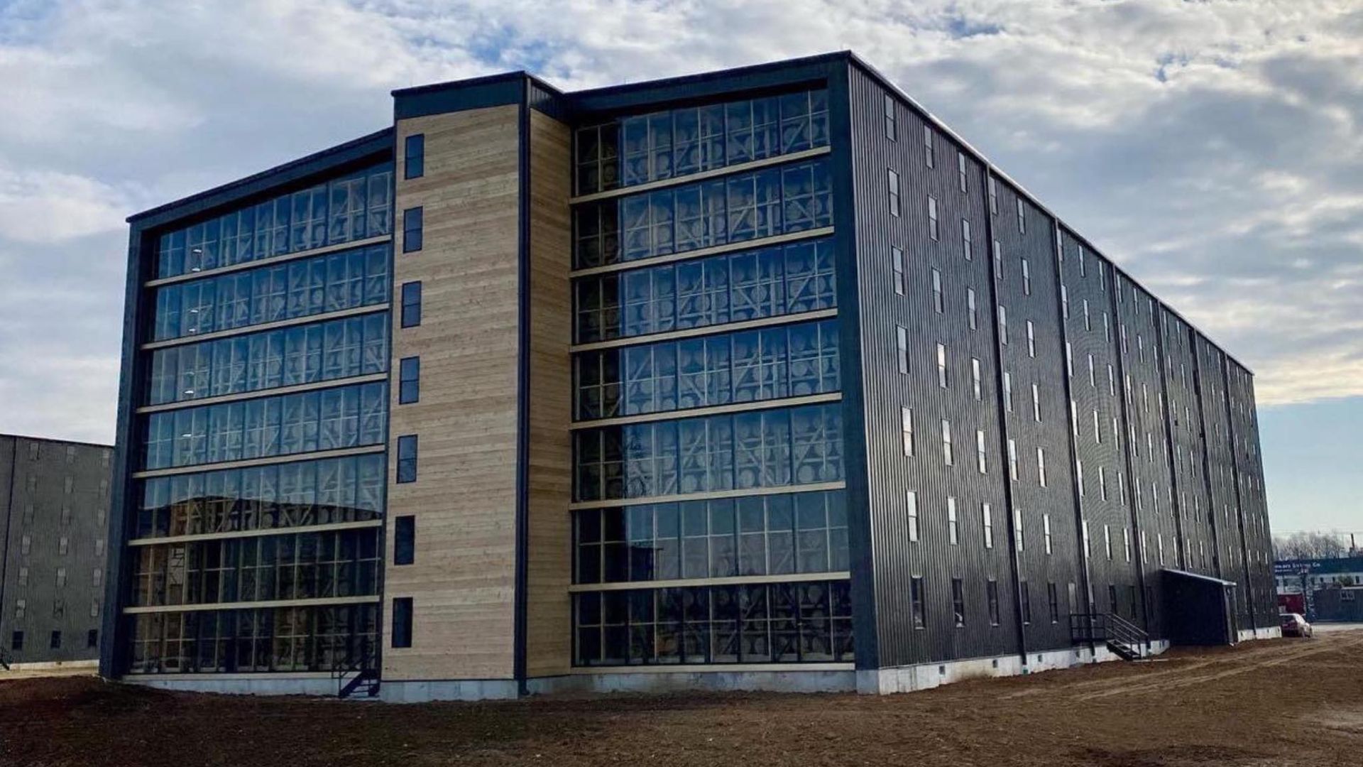 A large building with a lot of windows is sitting on top of a dirt field.