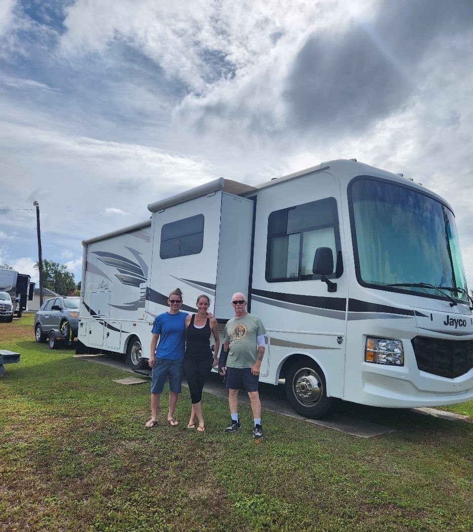 A group of people are standing in front of a rv.