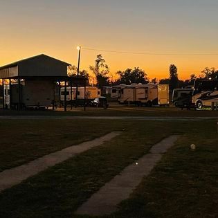 A group of rvs are parked in a field at sunset.