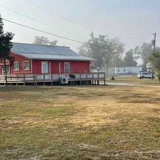 A red house with a white roof is sitting in the middle of a grassy field.