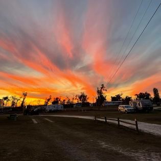 A sunset over a trailer park with a fence in the foreground.